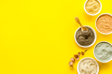 cosmetic clay - Yellow, red, white, blue and black dry powder - top-down flat lay on yellow table space for text