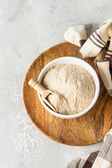 Buckwheat flour and a small wooden scoop with flour in a bowl, light grey concrete background. Gluten free flour, healthy nutrition. Top view.