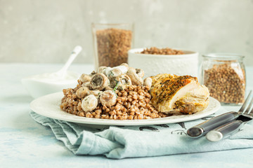 Grilled chicken breast, mushroom and tasty buckwheat porridge. Dietary balanced food. Light grey concrete background. Toned image. 