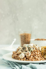Grilled chicken breast, mushroom and tasty buckwheat porridge. Dietary balanced food. Light grey concrete background. Toned image.