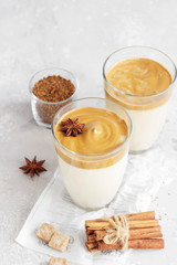 Iced Dalgona coffee in tall glass with spices. A trendy fluffy creamy whipped coffee. Korean coffee drink. Light grey concrete background. 
