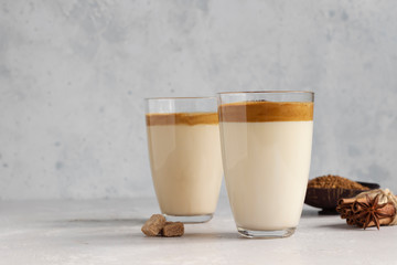 Iced Dalgona coffee in tall glass with spices. A trendy fluffy creamy whipped coffee. Korean coffee...