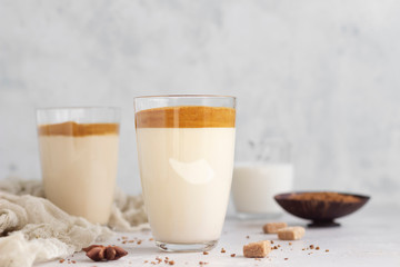 Tasty fresh iced coffee, Dalgona coffee. Trend Korean drink with instant coffee in glass on light grey table. 