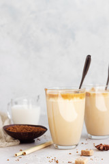 Tasty fresh iced coffee, Dalgona coffee. Trend Korean drink with instant coffee in glass on light grey table. 