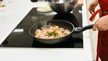 the cook is cooking langoustines. cook in the kitchen. wild shrimp.