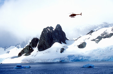Helicopter patrolling over glaciers and icebergs in Errera Channel at Culberville Island, Antarctica