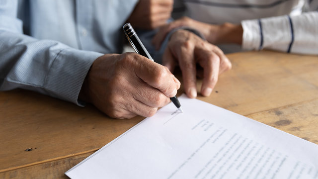 Close up older man putting signature on legal documents, mature couple, wife and husband making purchasing or investment deal, taking loan or buying new house, senior male signing contract