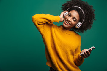 Smiling african curly woman listening music