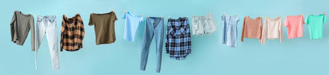 Clean laundry hanging on line against color background