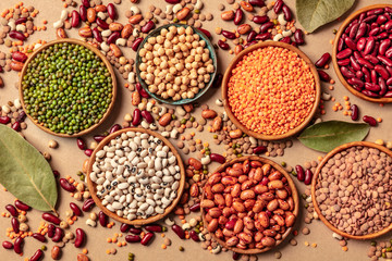 Legumes assortment, shot from above on a brown background. Lentils, soybeans, chickpeas, red kidney beans, a vatiety of pulses