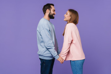 Positive loving couple posing over purple background.