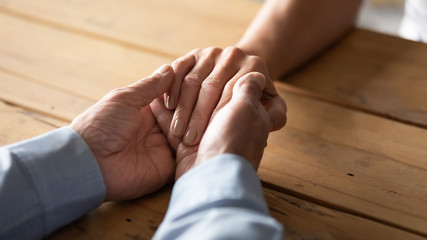 Loving caring older husband holding mature wife hand on wooden table close up, support and empathy concept, elderly family expressing empathy and understanding, trusted relationship in marriage