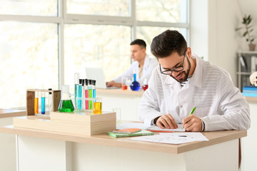 Fototapeta premium Young man at chemistry lesson in classroom