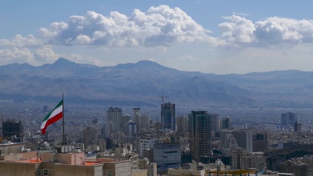 Iranian flag waving in the middle of the capital city of Tehran in a sunny day