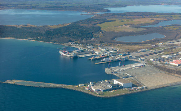 An aerial view of the industrial and ferry port of Mukran on the German island of R&uuml;gen in the Baltic Sea. There is a large industrial ship and a ferry in the harbor. Lagoons can be seen at the back.