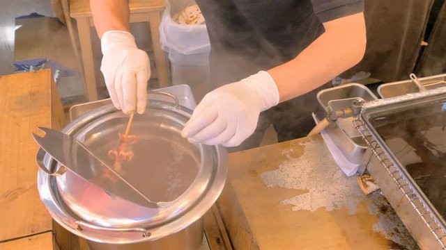 The man dipping the food in stick in the hot water in Tokyo Japan