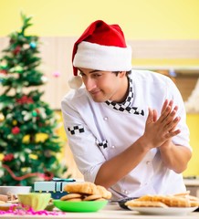 Young chef husband working in kitchen at Christmas eve