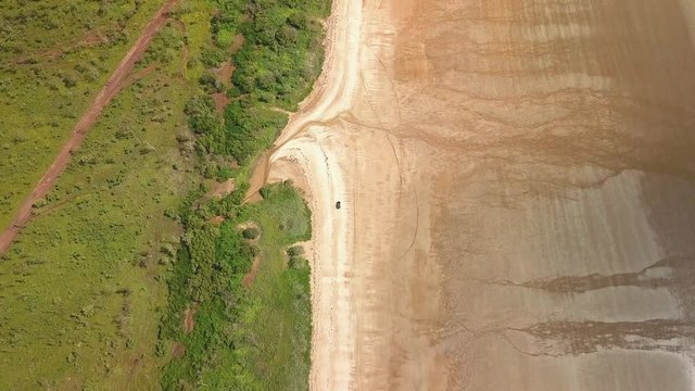 Aerial overhead tracking shot of a car driving on Gun Point Beach, near Darwin in Australia.
