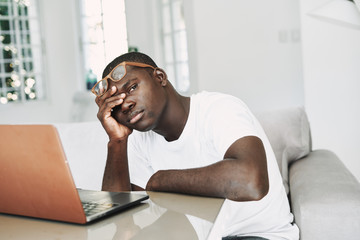 man of african appearance at home in front of a laptop