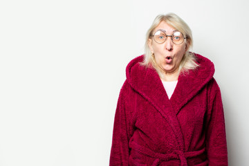 Portrait of an old friendly woman with a surprised face in a casual coat and glasses on an isolated...