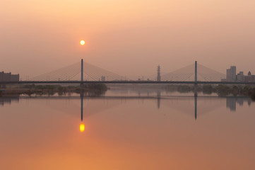 Fototapeta na wymiar 淀川と橋とオレンジ色の朝日