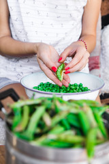 Woman preparing fresh organic peas and taking it out from a shell.