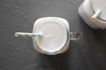 Coconut milk in a glass jar on a gray surface, top view. Flat lay, overhead, from above. 