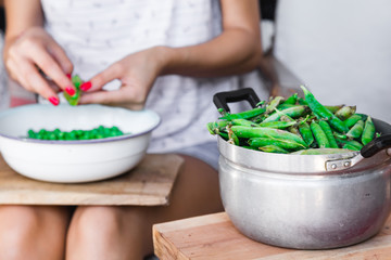 Woman preparing fresh organic peas and taking it out from a shell.