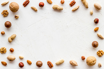 Fototapeta na wymiar Nuts background - healthy snacks concept - on white table top-down frame copy space