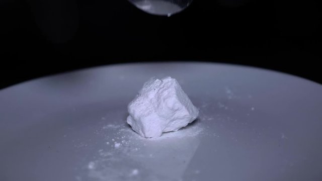 Cocaine Rock on a white plate gloves on with black background choping the rock with a spoon 23fps, 180fps slowmotion 1080P.mp4