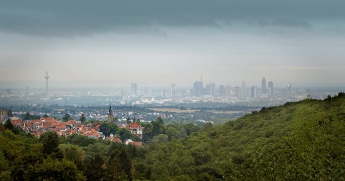 A historical German town in front of Frankfurt´s modern skyline. Dark moving clouds, viewed from the Taunus hills.