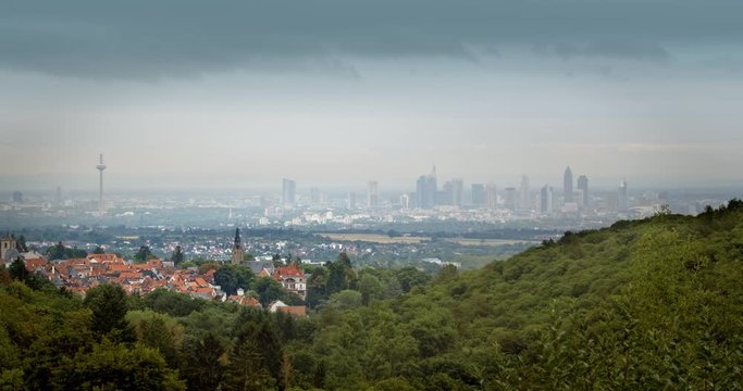 A historical German town in front of Frankfurt&acute;s modern skyline. Dark moving clouds, viewed from the Taunus hills.