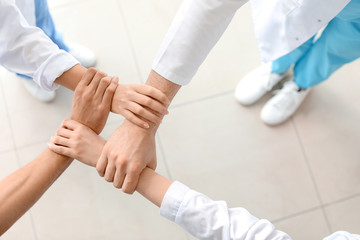 Group of doctors holding hands together in clinic, top view. Unity concept