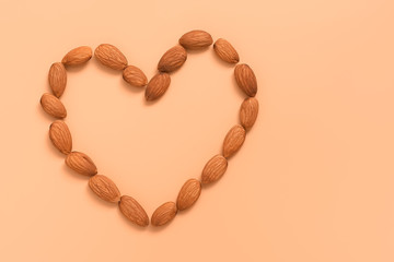 Flat lay nuts almonds in the shape of a heart on a pink pastel background. Creative layout. Top view, place for text.