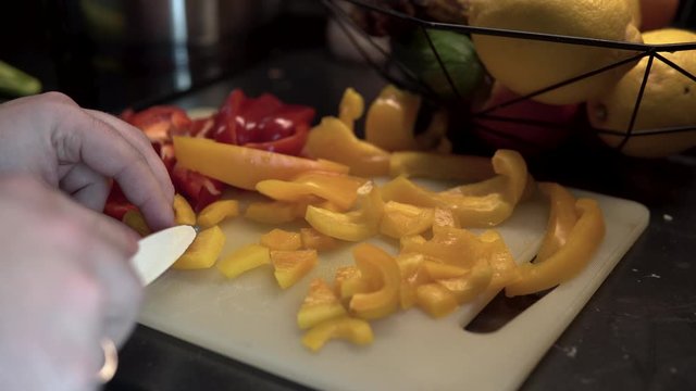 Close up slicing red and yellow peppers, preparing healthy vegetable food