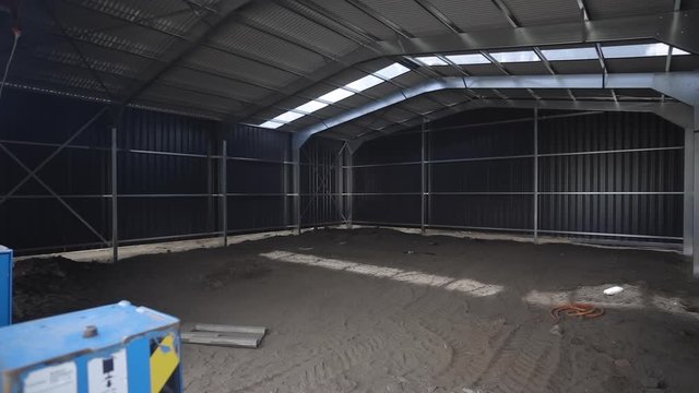 Panning from left to right of a large industrial shed that is under construction but near completion.