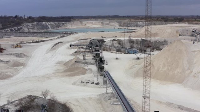 Industry at faxe kalkbrud with heavy machinery working with limestone quarry on an overcast day from aerial drone view