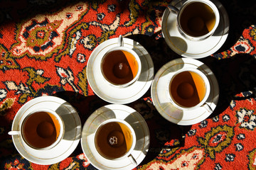 vintage soviet porcelain cups of tea with saucers on turkish carpet, traditional tea ceremony,...
