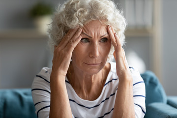 Sad mature woman touching temples close up, feeling unwell, high blood pressure, mental disorder or...