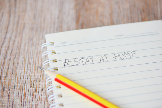 Write words stay at home on notebook paper with pencil pandemic of coronavirus or Covid-19 and social distancing staying at home with self quarantine to stop outbreak and protect virus spread