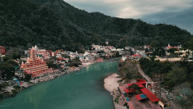 Drone shot, Aerial View, Lakshman Jhula bridge and Tera Manzil Temple, Trimbakeshwar in Rishikesh, Ganges River, holy town and travel destination in India.  