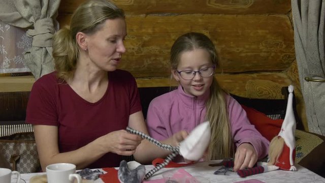 Daughter and mother make toys at the table for the New Year holiday. Family evening in the run-up to the holiday two generations of craftswomen make soft toys with their own hands.