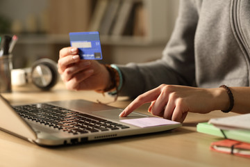 Student hands paying with credit card on laptop at night