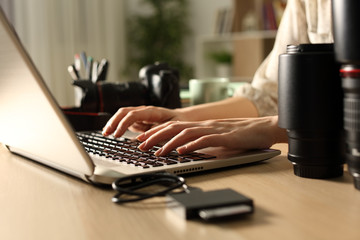 Photographer hands transfering card files to laptop at night