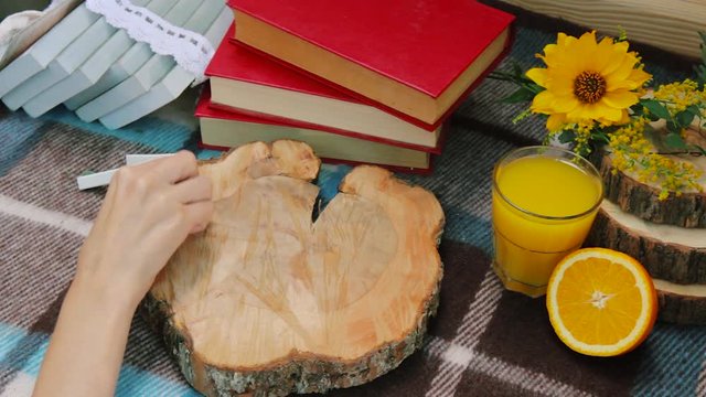 Young girl writes word hello. Books and orange juice on rustic background. 
