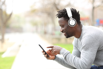 Black man listening music on headphones and phone