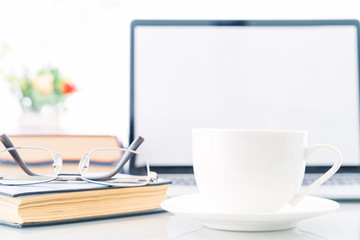 Cup of coffee with blank screen laptop computer on deck