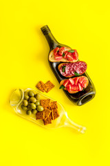 Wine appetizer on bottles as table on yellow table top view