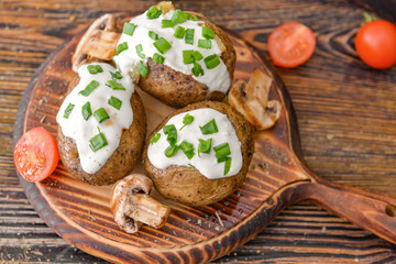 Tasty baked potato with sour cream and mushrooms on table