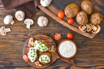 Fototapeta na wymiar Tasty baked potato with sour cream, vegetables and mushrooms on table
